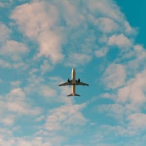 A plane flying through a blue sky with clouds