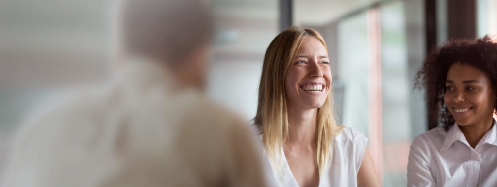 Photograph of two smiling women participating in a work meeting