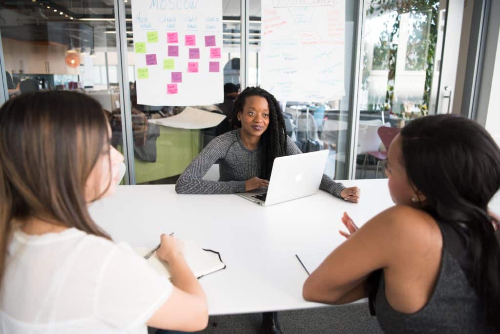 Photo of three female coworkers discussing a project together in a meeting